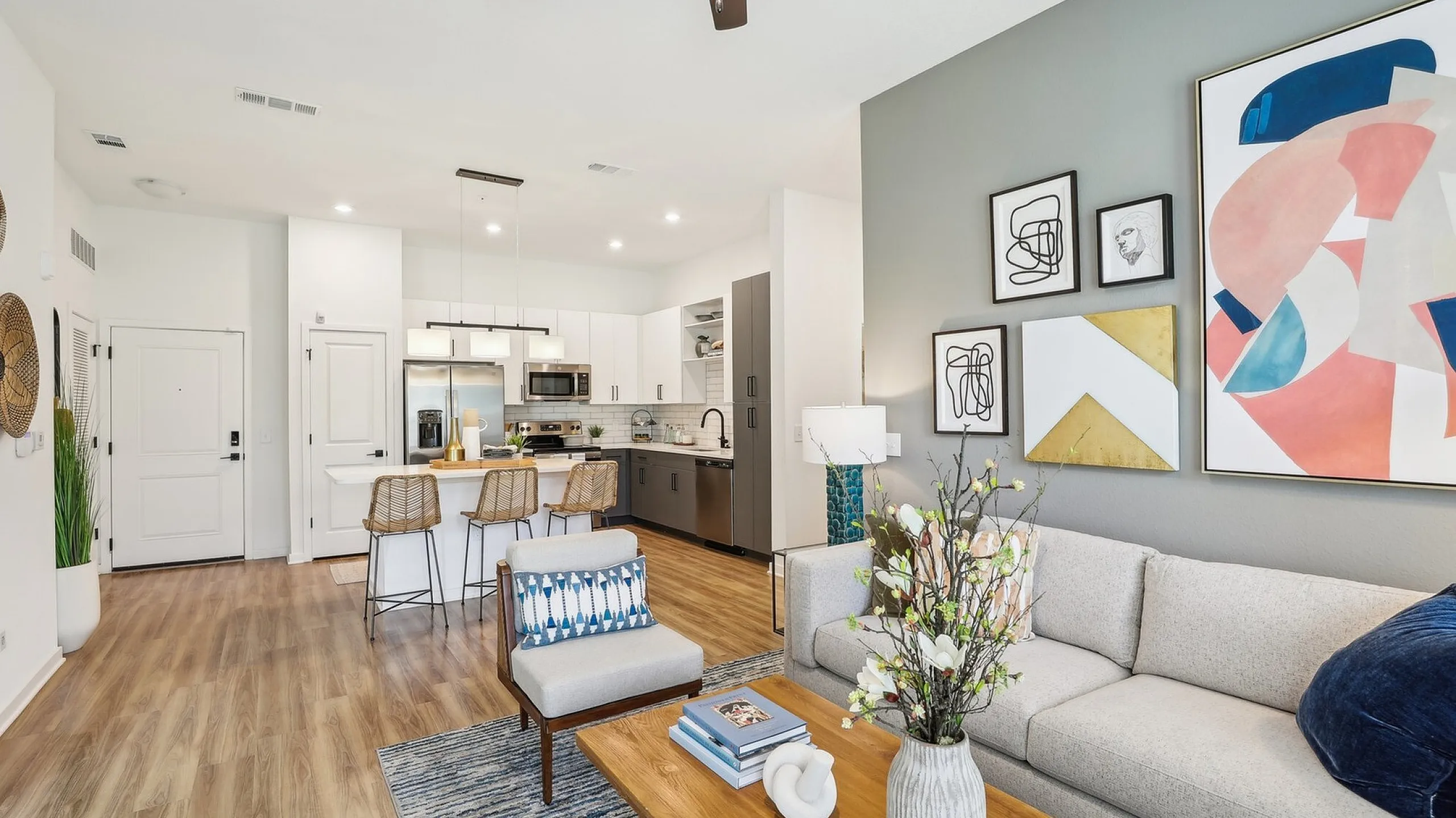 Chic open-plan living area with modern kitchen, stylish bar seating, and cozy lounge featuring vibrant decor and artwork.