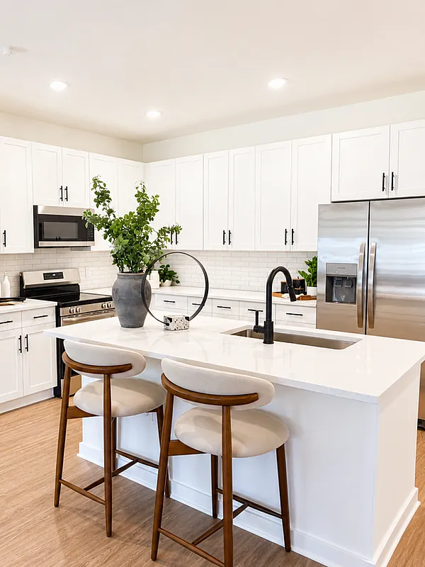 Elegant modern kitchen with sleek white cabinetry, stainless steel appliances, and a chic center island with comfortable seating.