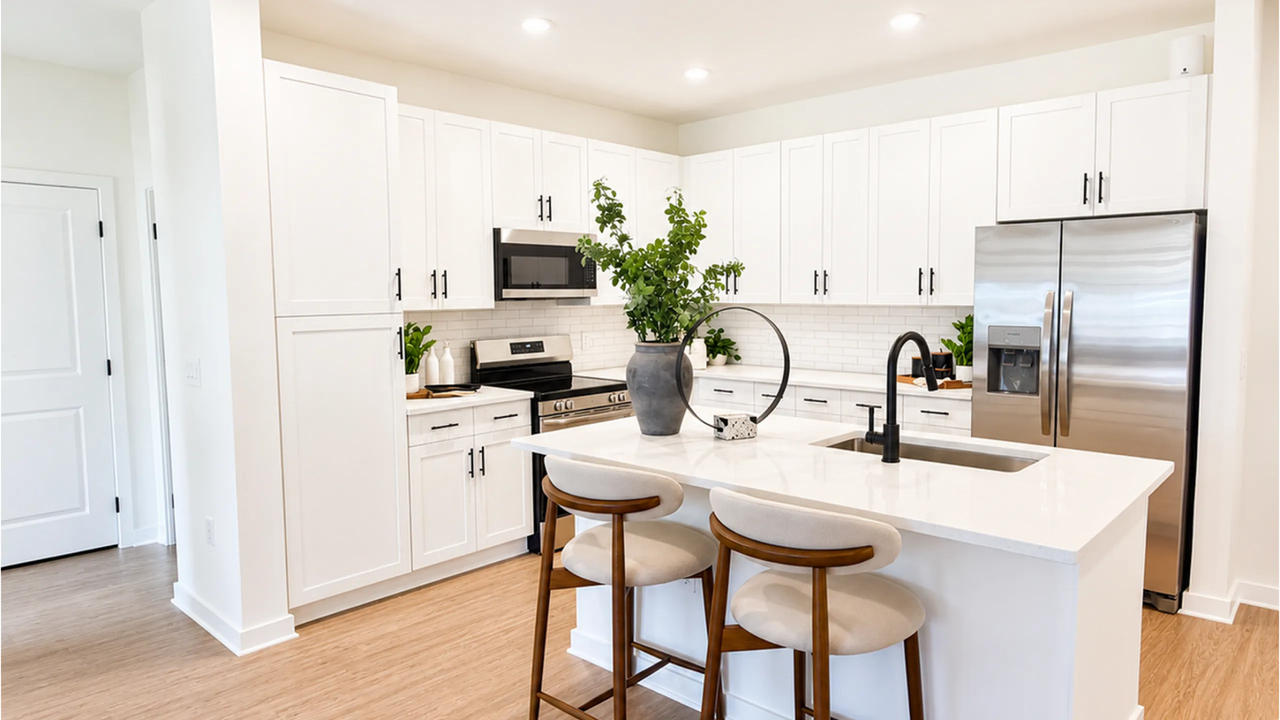 Modern kitchen featuring sleek white cabinetry, stainless steel appliances, and a chic breakfast bar with elegant seating.