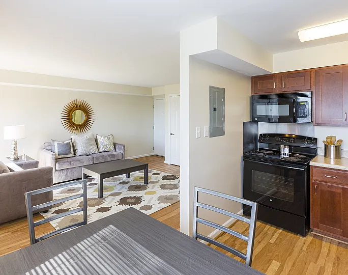 Bright and inviting open-plan living room and kitchen with modern appliances and stylish decor, featuring a plush sofa and elegant dining area.