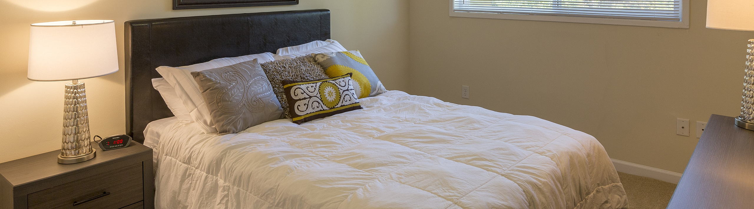 Inviting bedroom featuring a plush bed with elegant pillows, soft lighting, and a serene window view.
