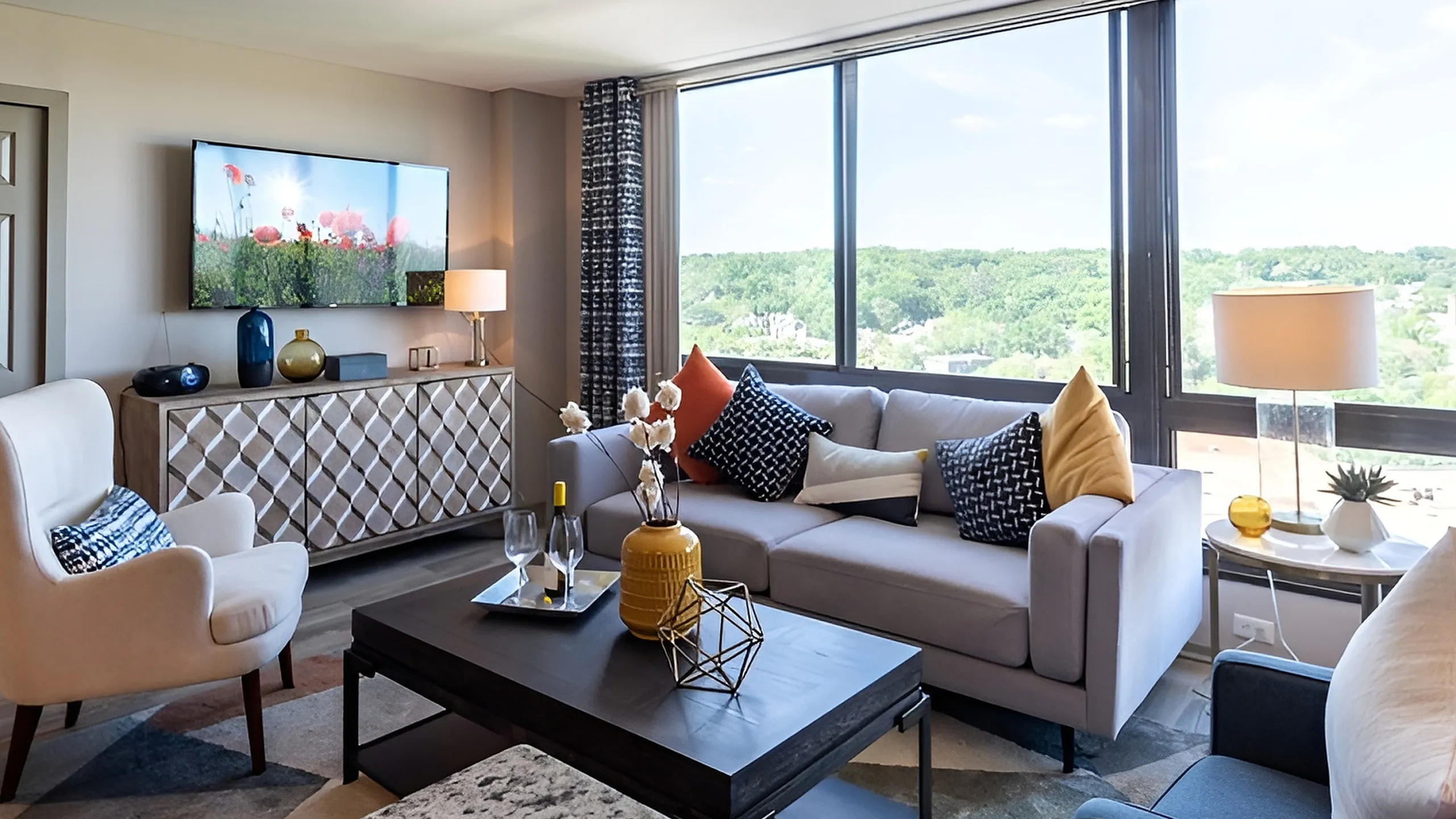 Bright and inviting living room with modern decor, featuring a plush sofa set, decorative cushions, and large windows offering a scenic view.