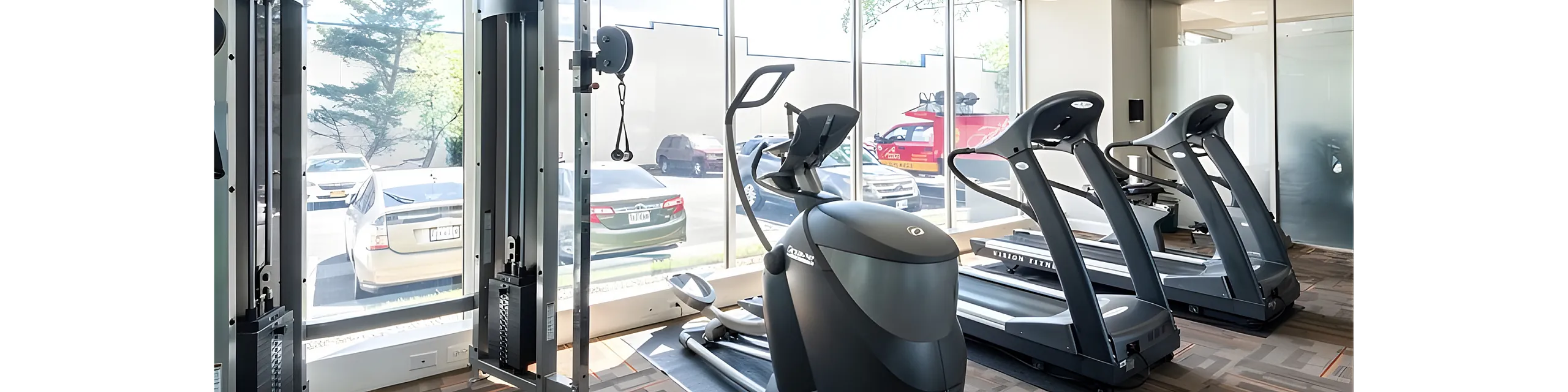 Bright, modern fitness center featuring state-of-the-art cardio equipment and expansive windows with natural light.