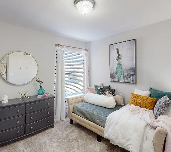 Cozy bedroom featuring a stylish daybed with colorful cushions, modern dresser, and elegant decor.