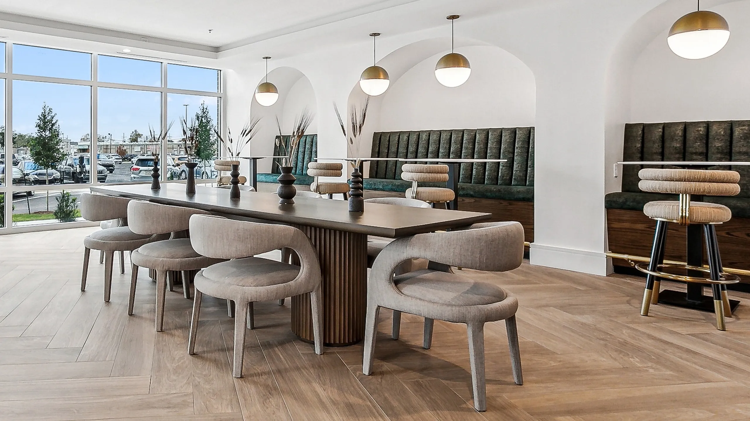 Bright and inviting communal space with stylish modern decor, featuring elegant pendant lighting, comfortable seating, and expansive windows offering scenic views.
