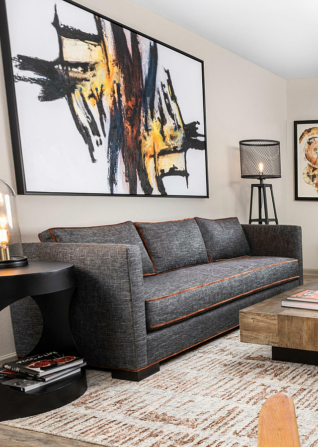 Chic apartment living room with modern art, plush sofa, and stylish wooden accents, offering a blend of comfort and contemporary design.