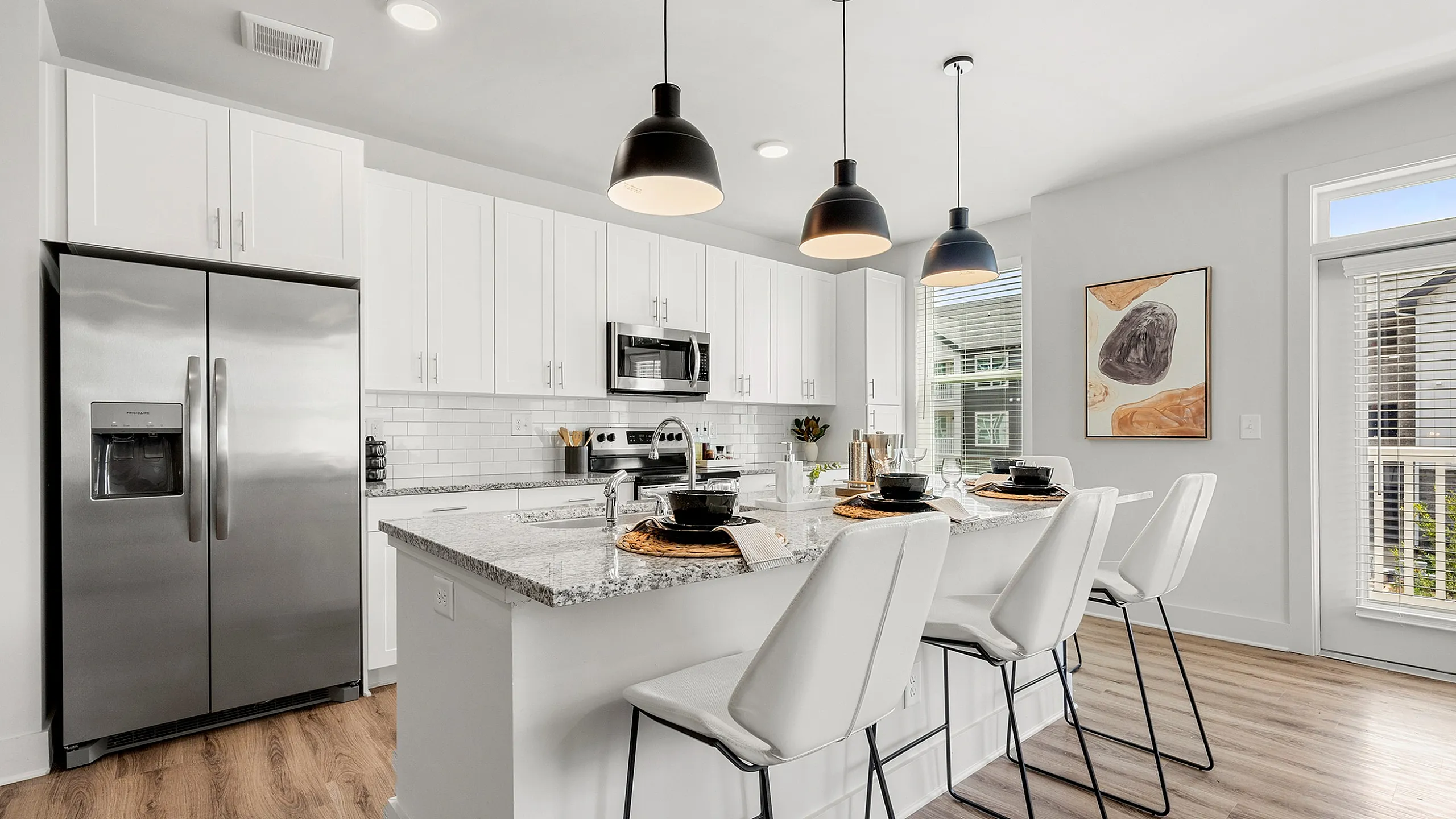 Contemporary kitchen with sleek stainless steel appliances, elegant pendant lights, and an inviting breakfast bar with stylish seating.