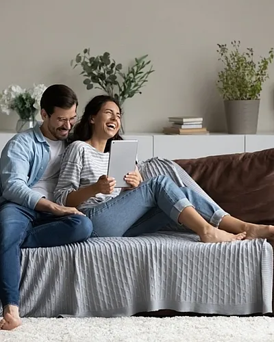 Happy couple enjoying cozy living room with modern decor and comfortable brown sofa, creating a warm and inviting atmosphere.