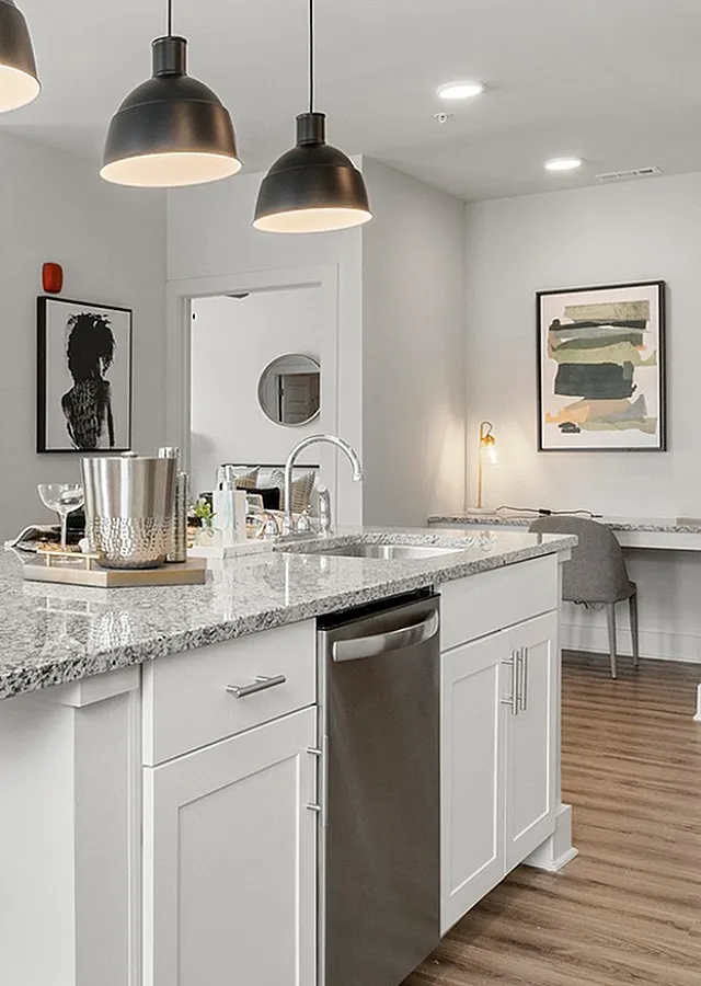 Modern open-concept living area with sleek kitchen island, stylish pendant lighting, and large window showcasing a scenic view.
