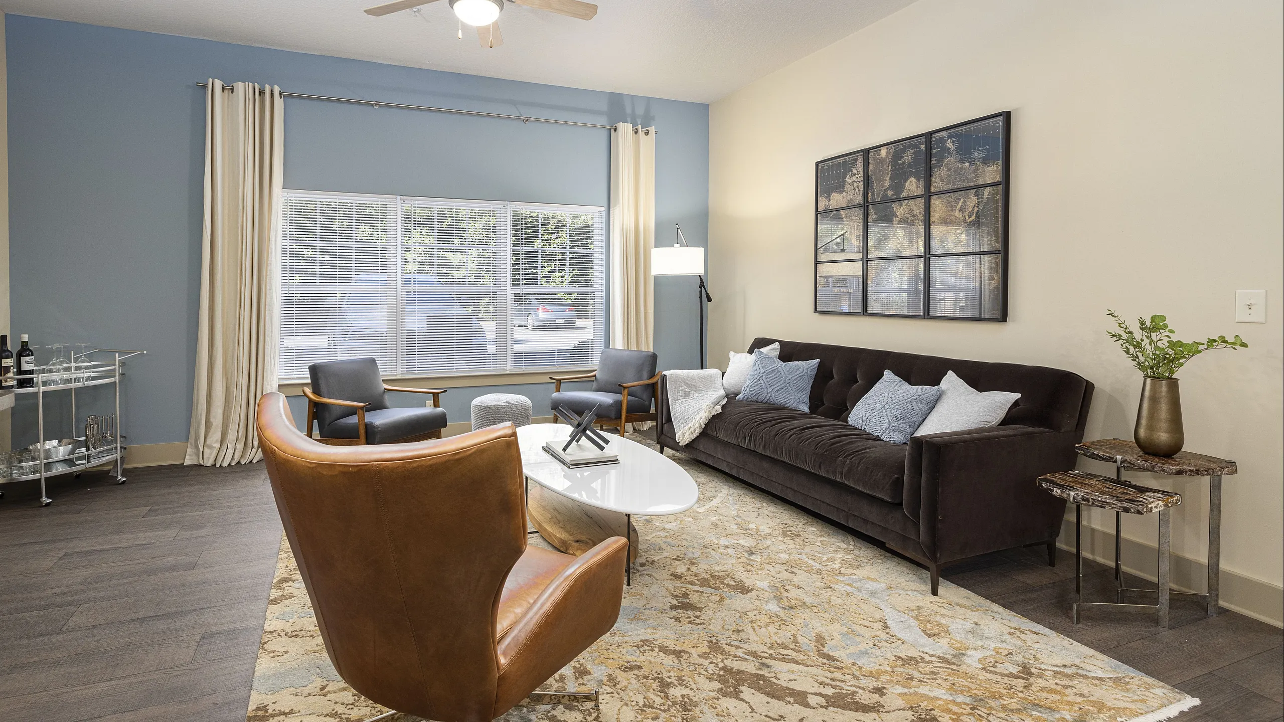 Inviting living room featuring a plush dark sofa, stylish leather chair, and chic decor on elegant hardwood floors.