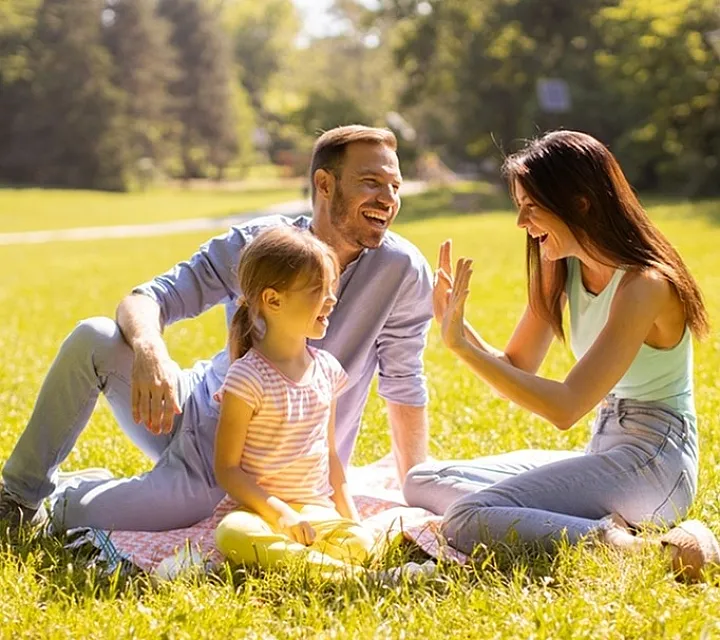 Joyful family enjoying a sunny day on a lush green lawn, showcasing a vibrant outdoor lifestyle.