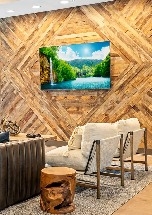 Chic lounge area with luxurious seating, rustic wood accent wall, and vibrant landscape artwork.