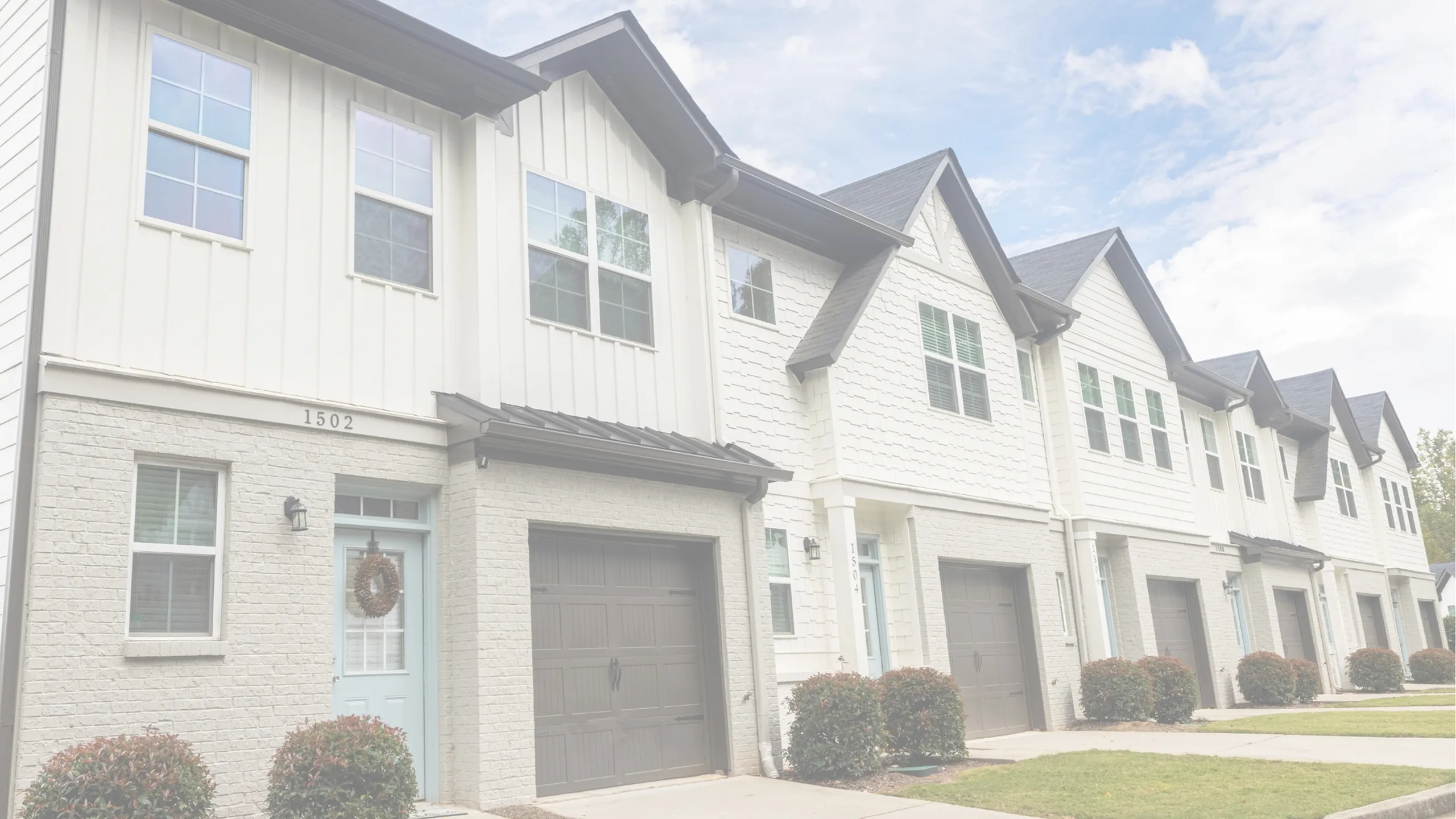 Charming townhouse exterior with modern brick and siding design, featuring elegant gray garages and manicured landscaping.