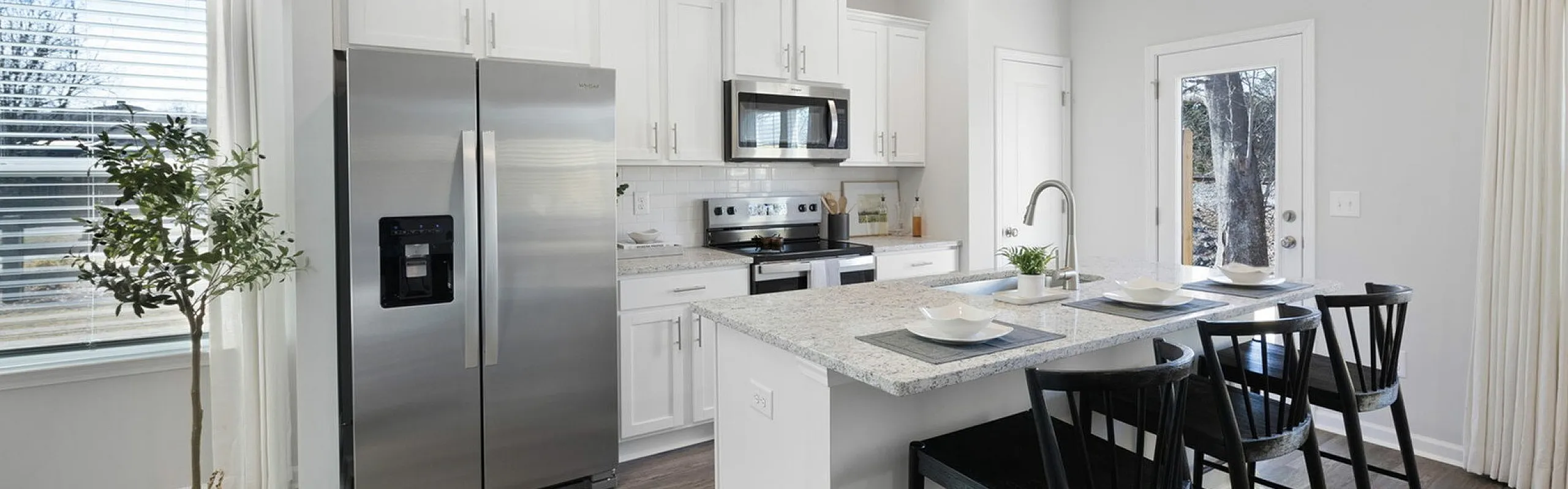 Modern kitchen with sleek stainless steel appliances, a chic island with seating, and bright natural light streaming in through large windows.