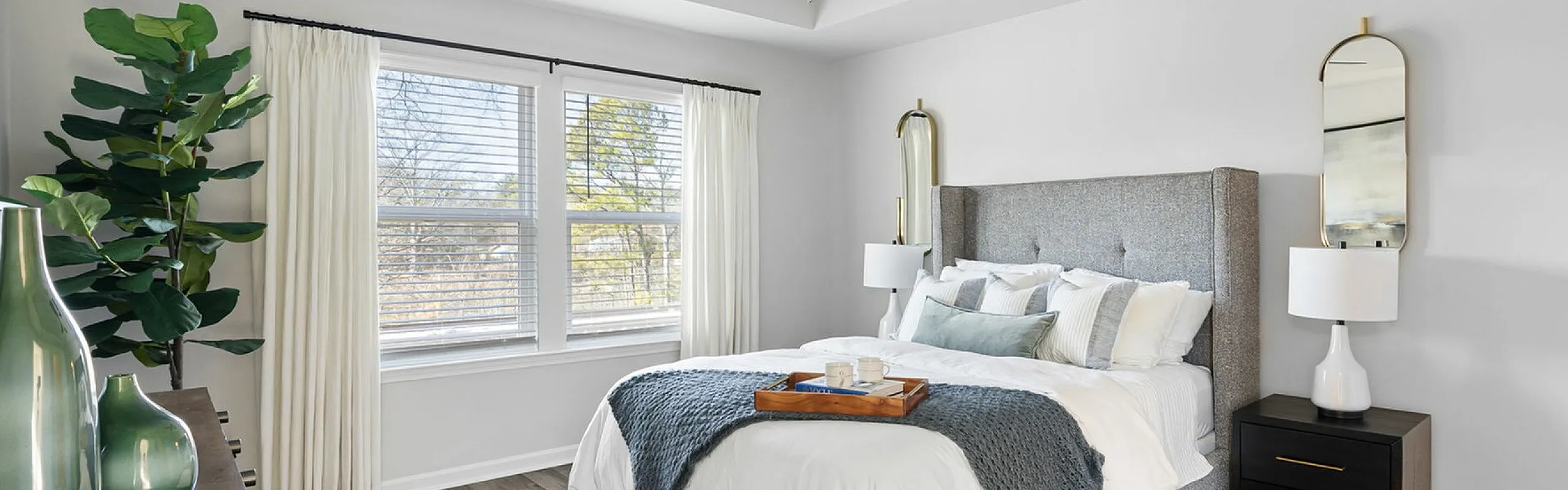 Bright and cozy bedroom with stylish laminate flooring, elegant bed with soft linens, and large windows offering natural light.