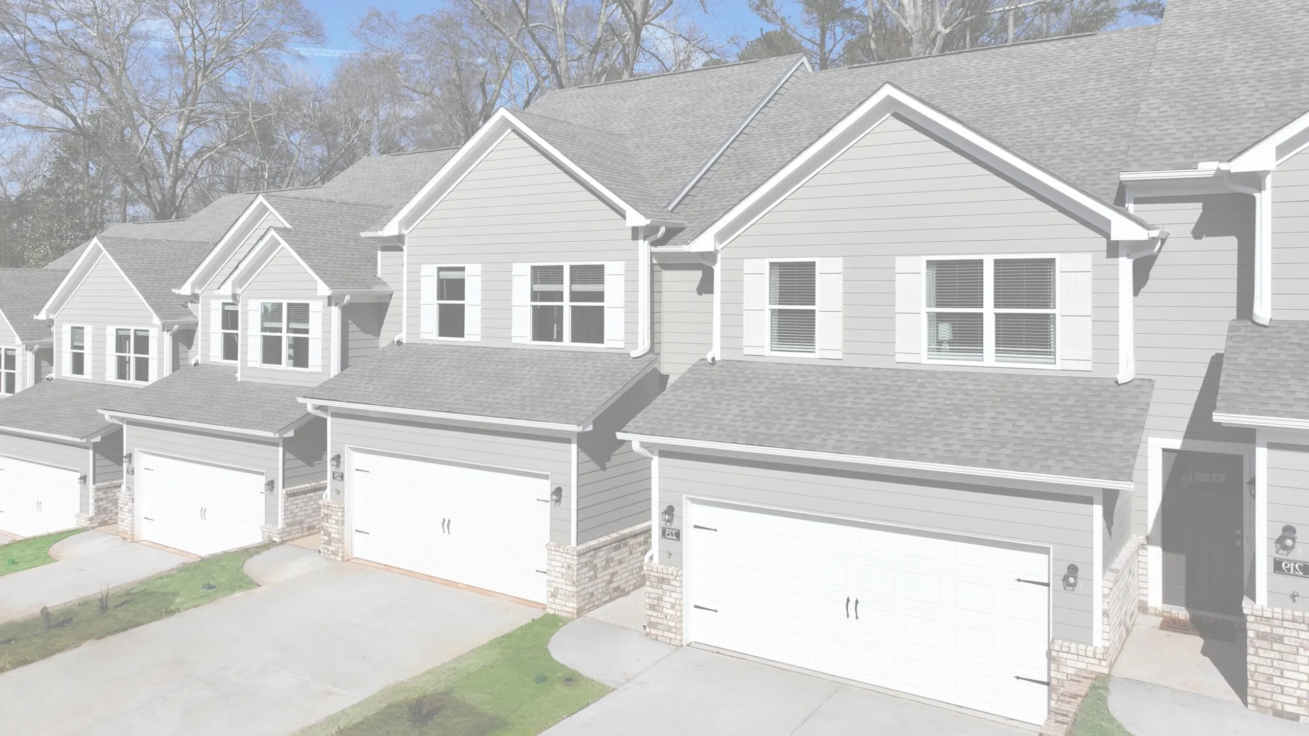 Charming row of modern townhouses with elegant gray exteriors, spacious two-car garages, and neatly landscaped driveways.