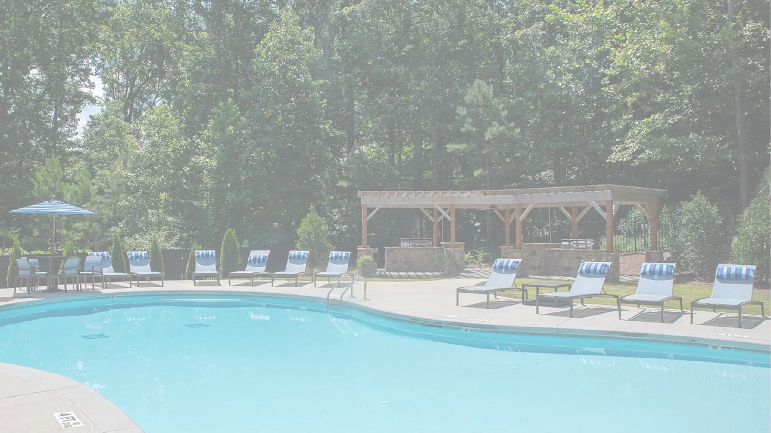 Inviting outdoor pool area with sun loungers, surrounded by lush greenery and a charming pergola.