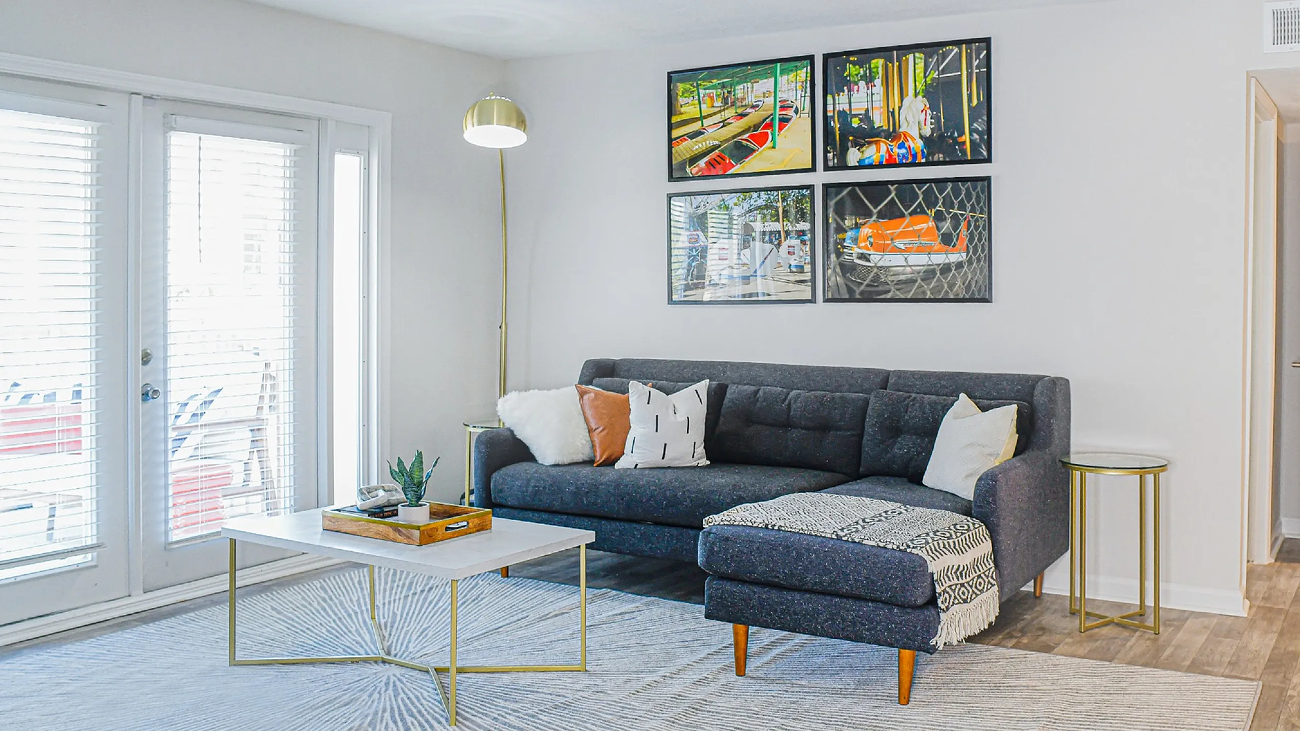 Chic living room featuring a modern gray sofa, elegant wall art, and abundant natural light through large windows.