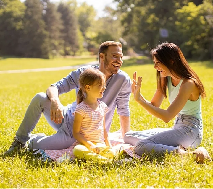 Joyful family enjoying a sunny day in a lush green park, epitomizing relaxation and happiness.