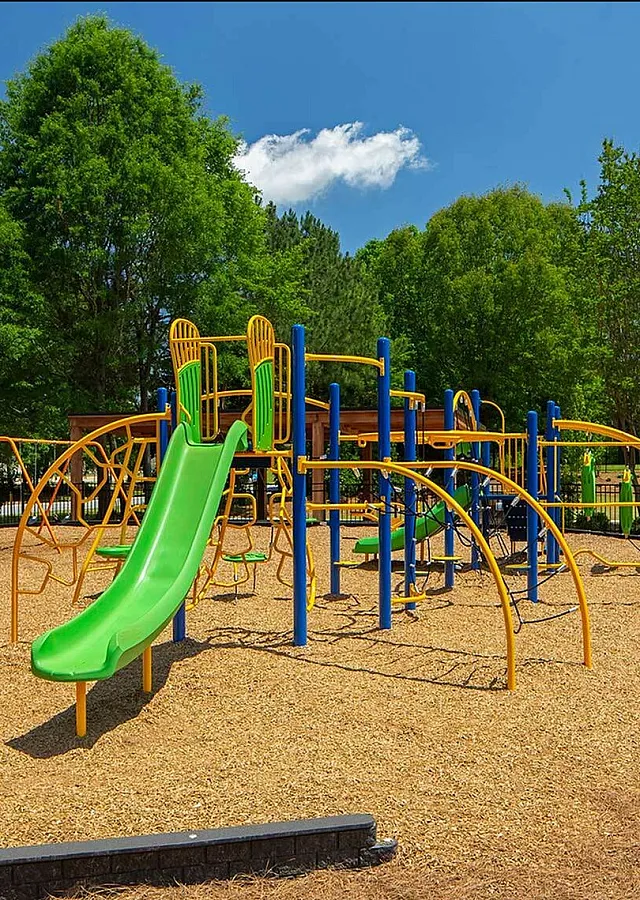 Vibrant playground with colorful slides and climbing structures surrounded by lush greenery, perfect for family fun.