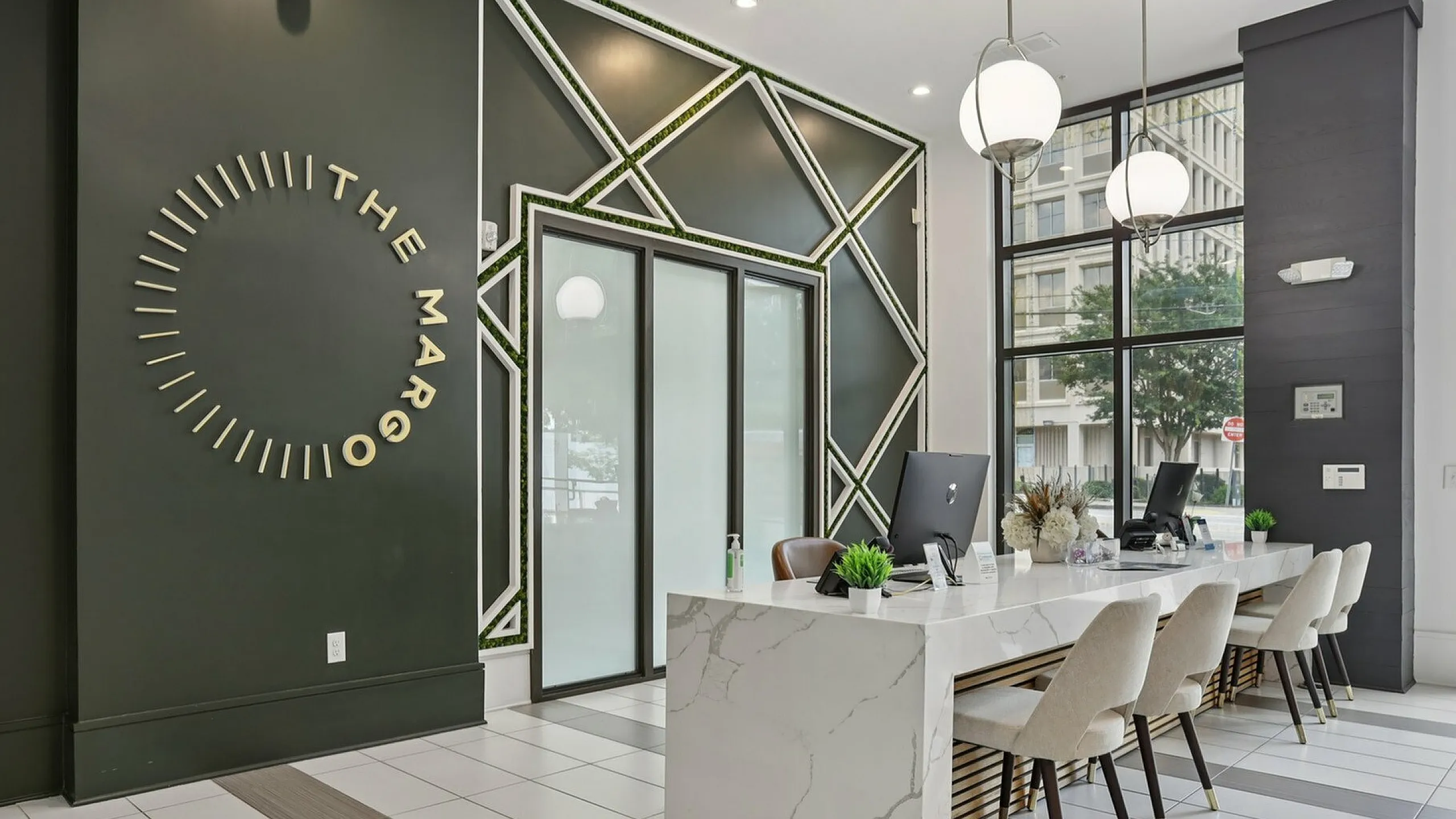 Luxurious apartment lobby at The Margo featuring modern design with marble desks, stylish seating, and striking geometric wall art.