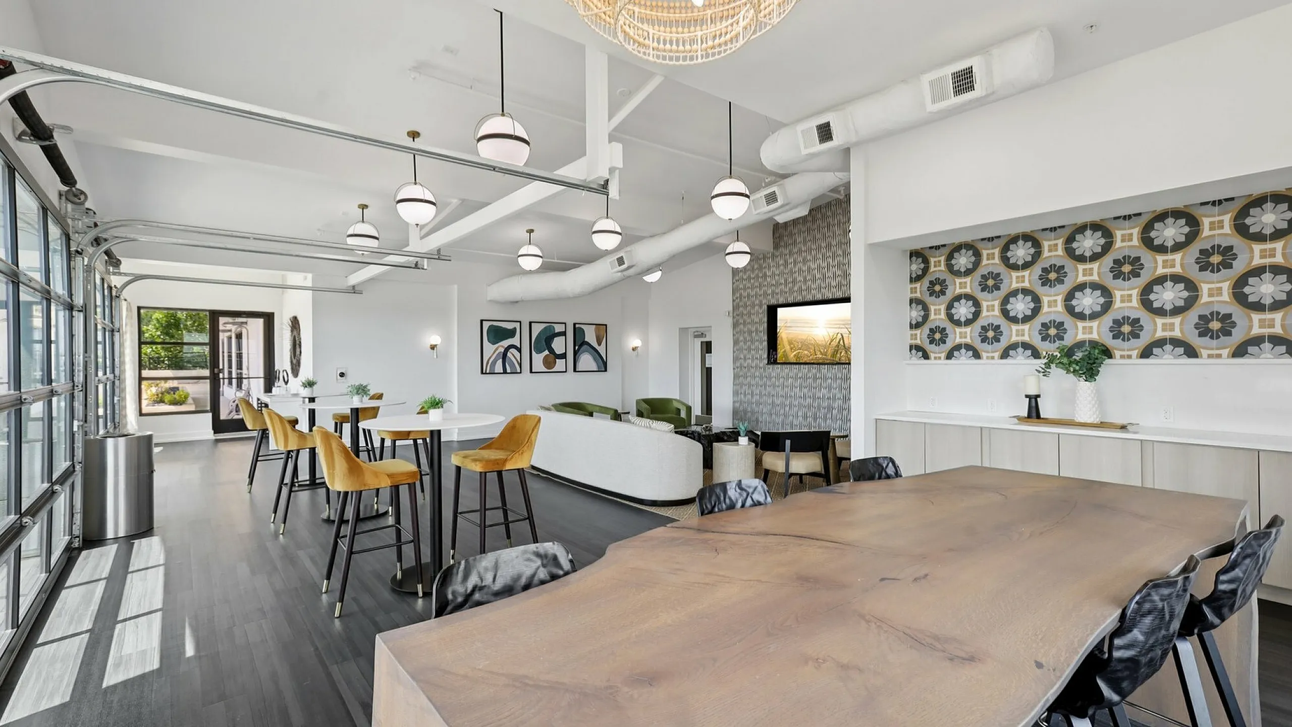 Chic communal space featuring modern decor, high ceilings with pendant lighting, and stylish seating with a view. Ideal for gatherings and relaxation.