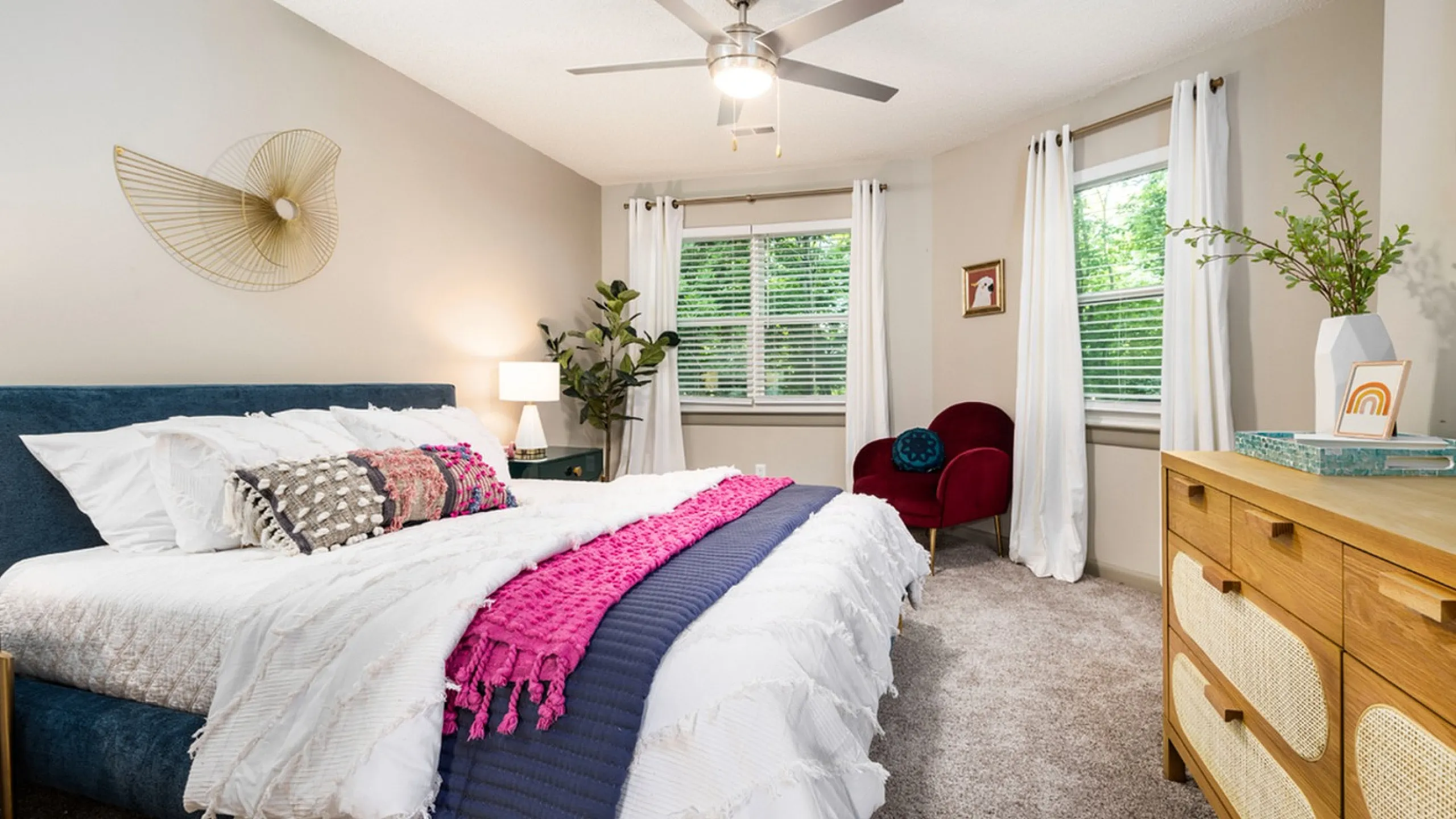 Charming bedroom with a plush bed, vibrant decor, chic wall art, and elegant furnishings, bathed in natural light.