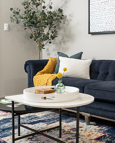Chic modern living room with a plush navy sofa, vibrant yellow accents, and contemporary wall art, ideal for relaxation.