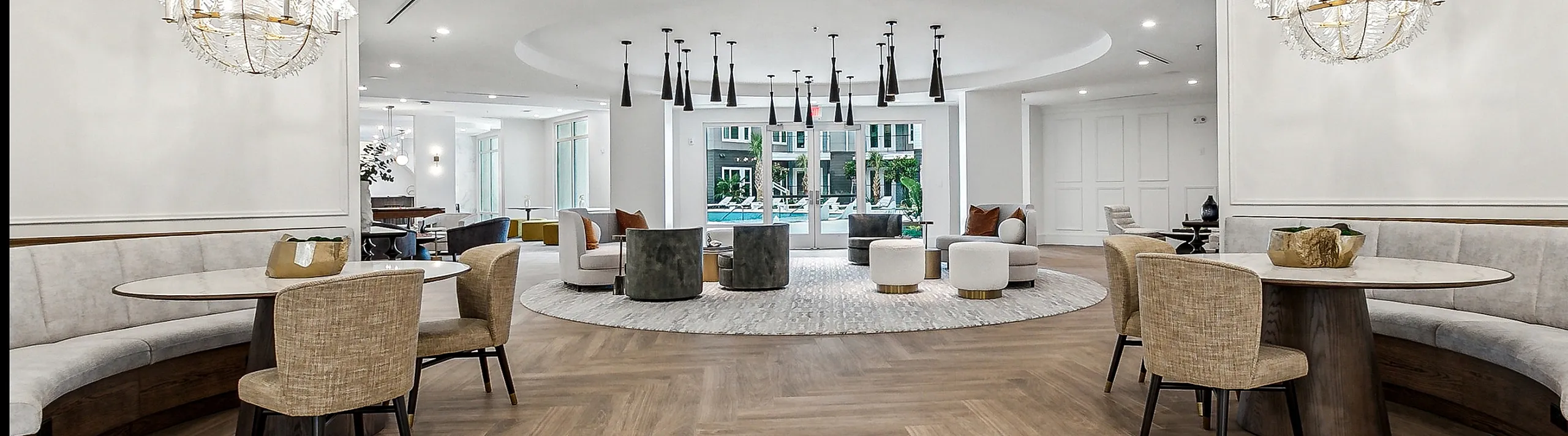 Luxurious open space with elegant round tables, plush seating, and modern chandeliers, ideal for socializing in style.