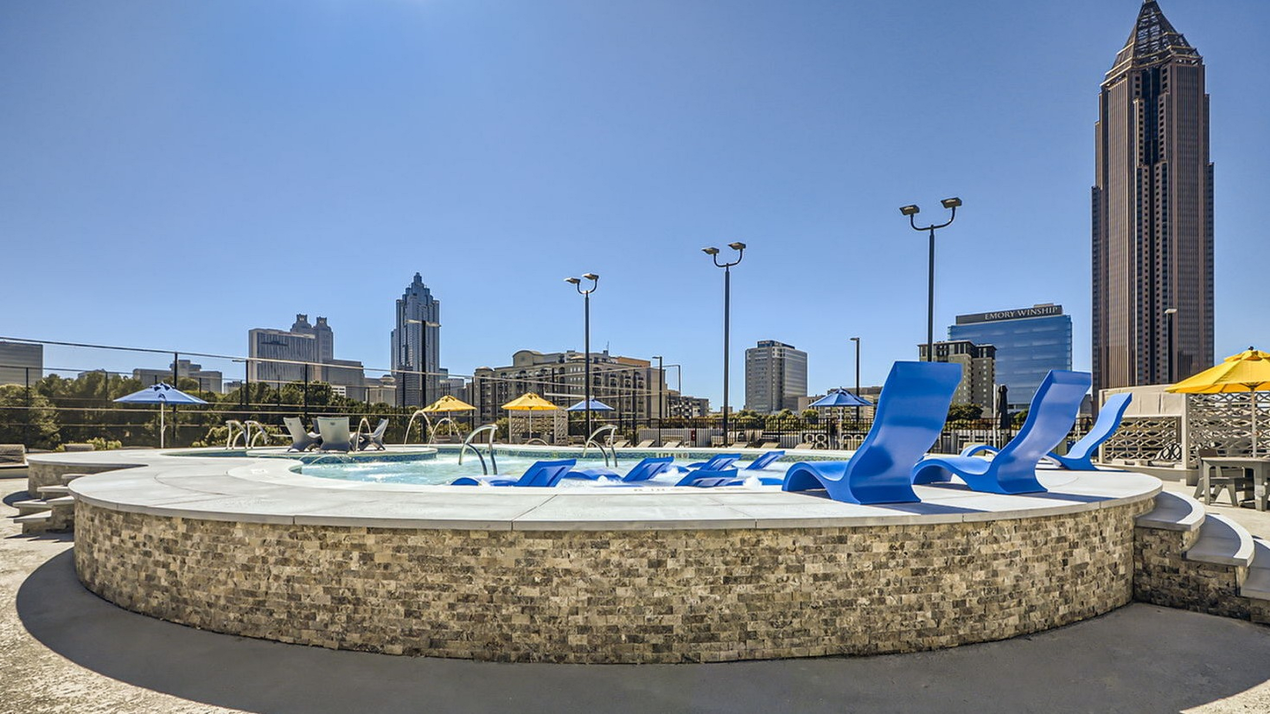 Stunning rooftop pool with luxurious blue loungers and vibrant city skyline views, featuring colorful umbrellas. Perfect urban retreat.
