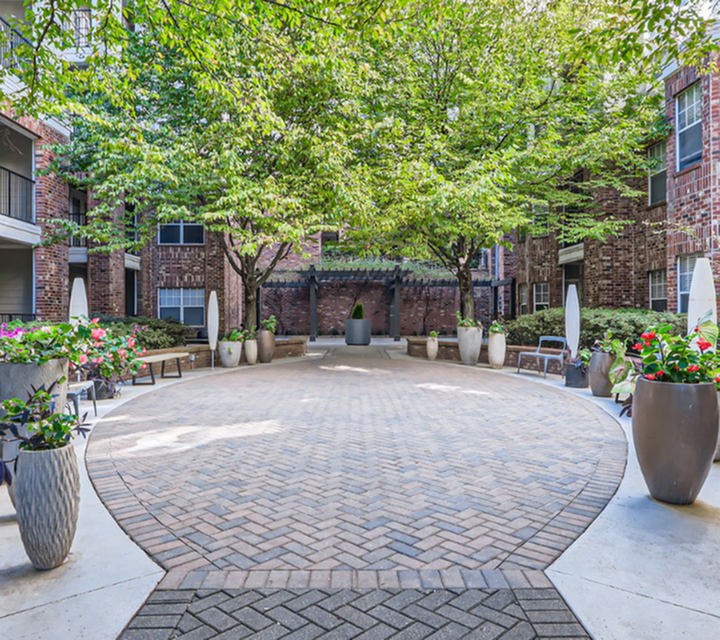 Charming courtyard with mature trees and vibrant flower planters, providing a serene and inviting outdoor space.