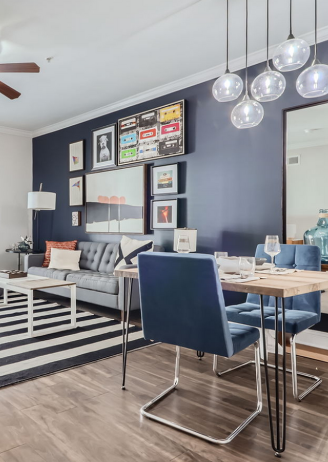 Chic living and dining area with modern decor, blue accents, and artistic wall gallery.