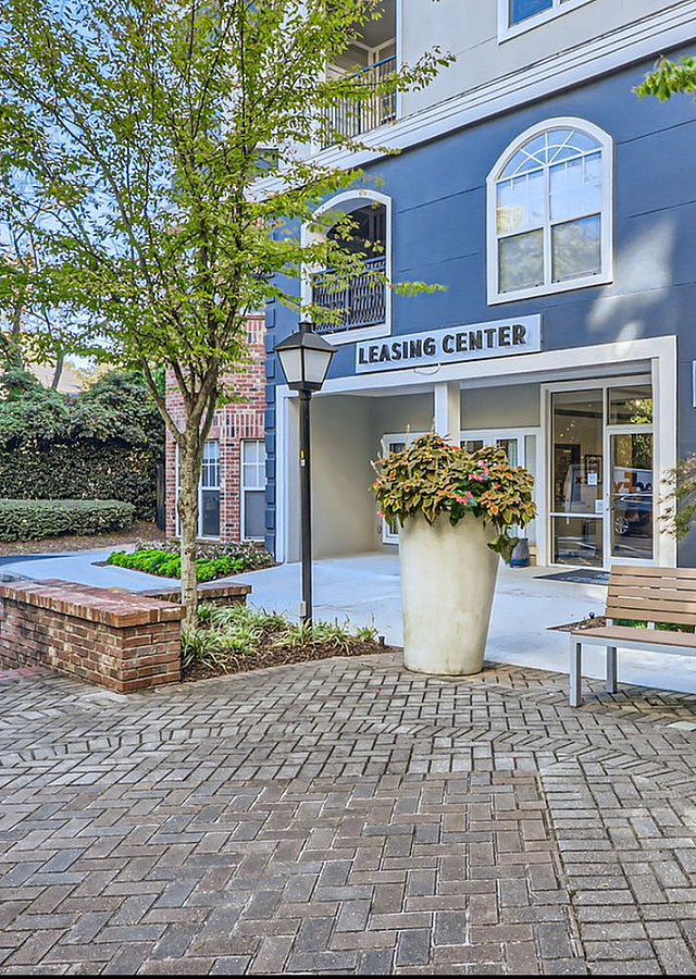 Welcoming leasing center entrance with elegant potted plants and a cozy bench, ideal for relaxation.