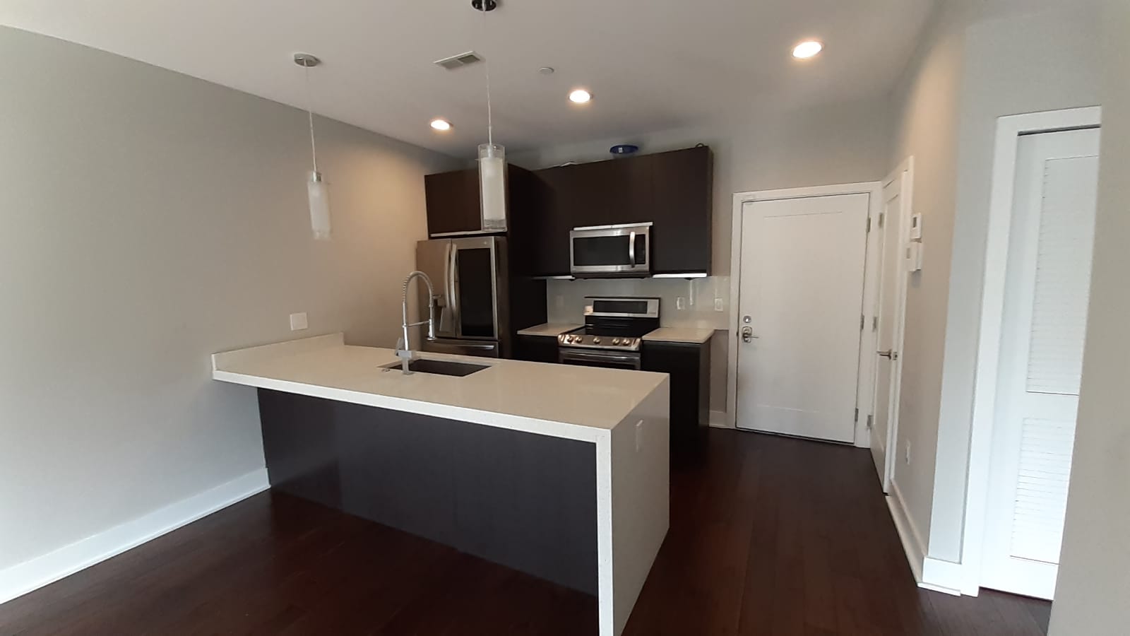 Modern kitchen featuring sleek cabinetry, an elegant island with a built-in sink, and stainless steel appliances.