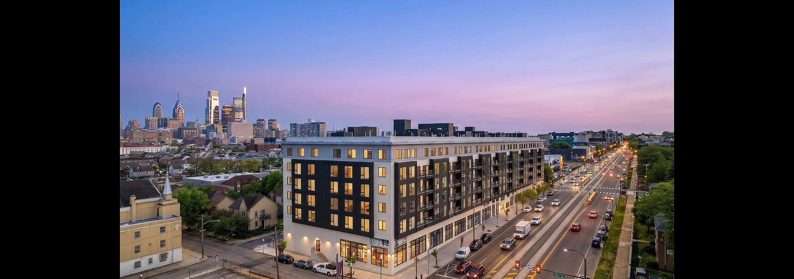 Modern urban apartment building with a vibrant city skyline at dusk, showcasing sleek design and bustling city life.