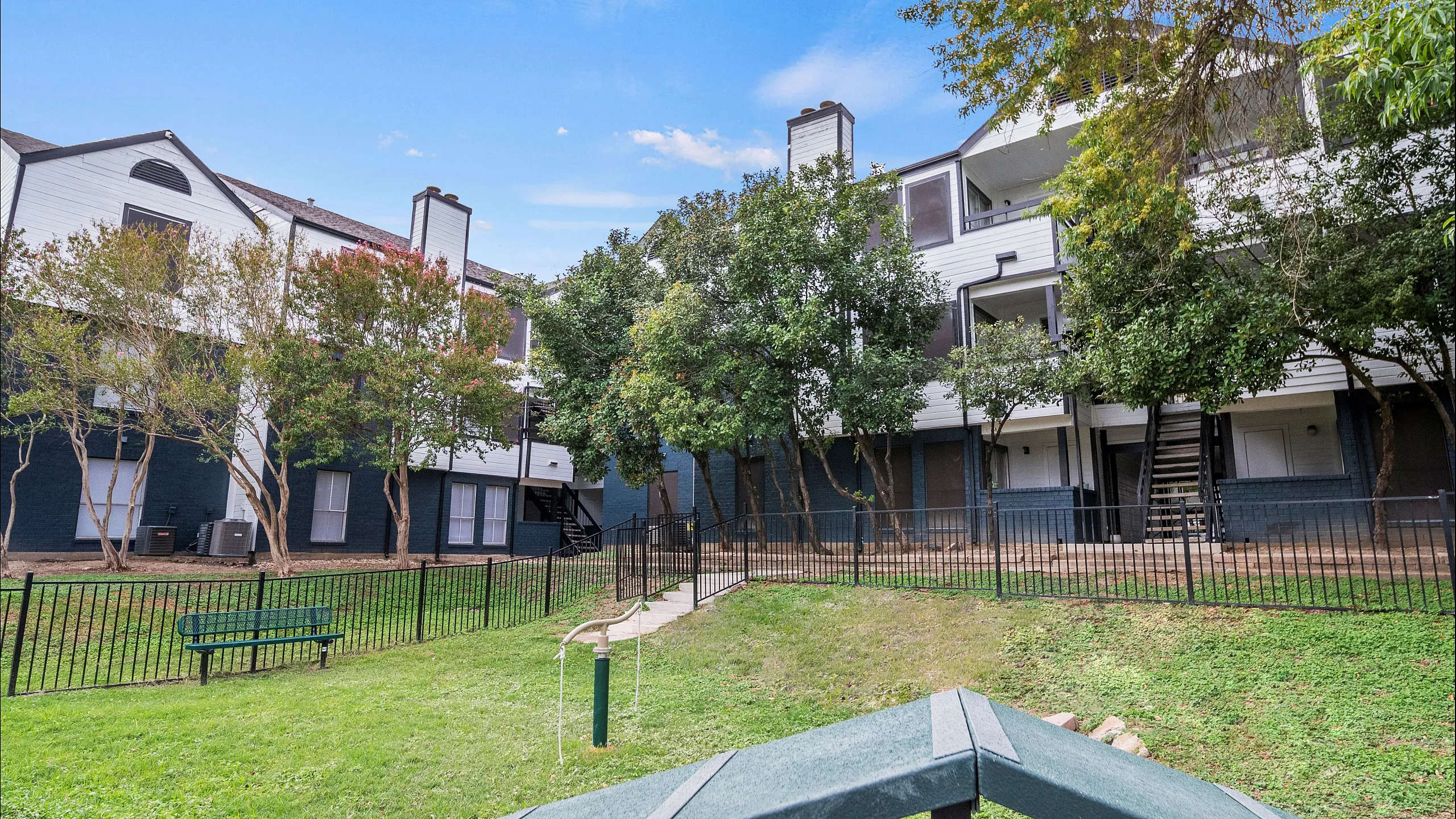 Charming apartment building surrounded by lush greenery and a peaceful courtyard with a scenic walkway.