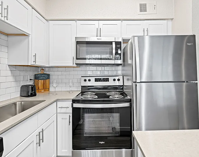 Modern kitchen with stainless steel appliances, sleek white cabinetry, and elegant subway tile backsplash.