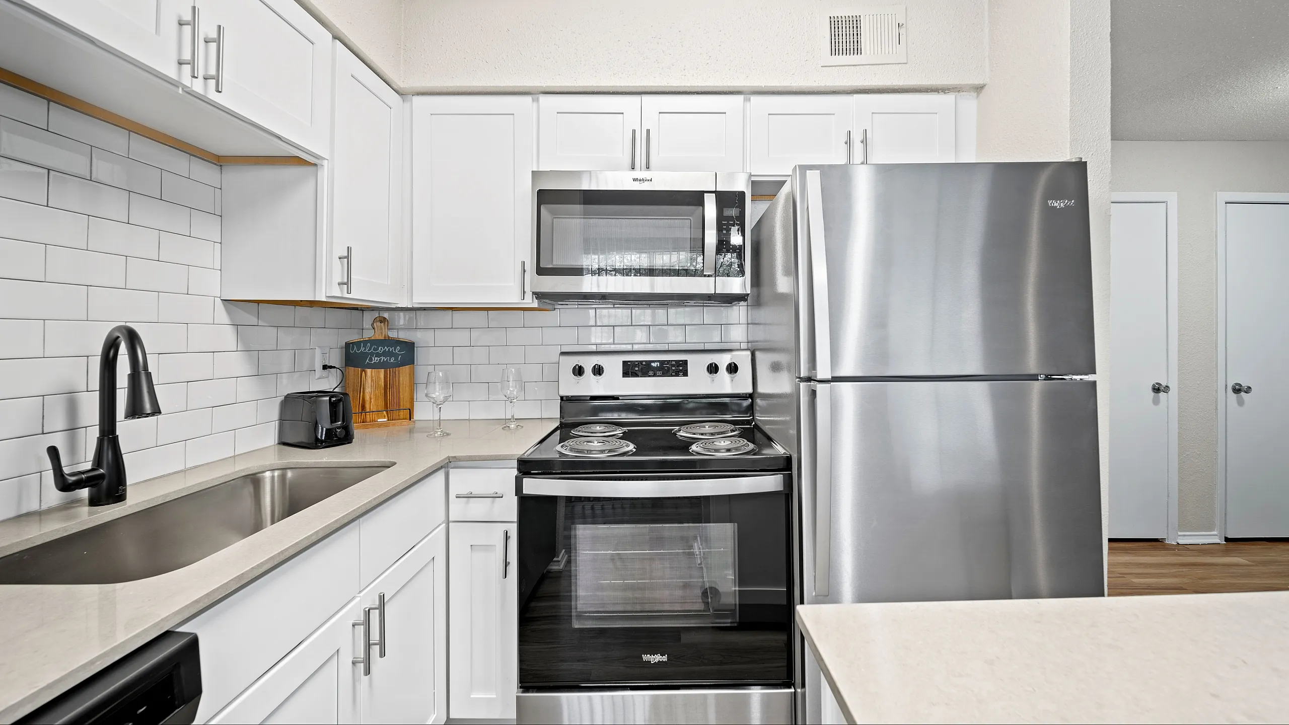 Modern kitchen with sleek stainless steel appliances, elegant white cabinetry, and stylish subway tile backsplash.