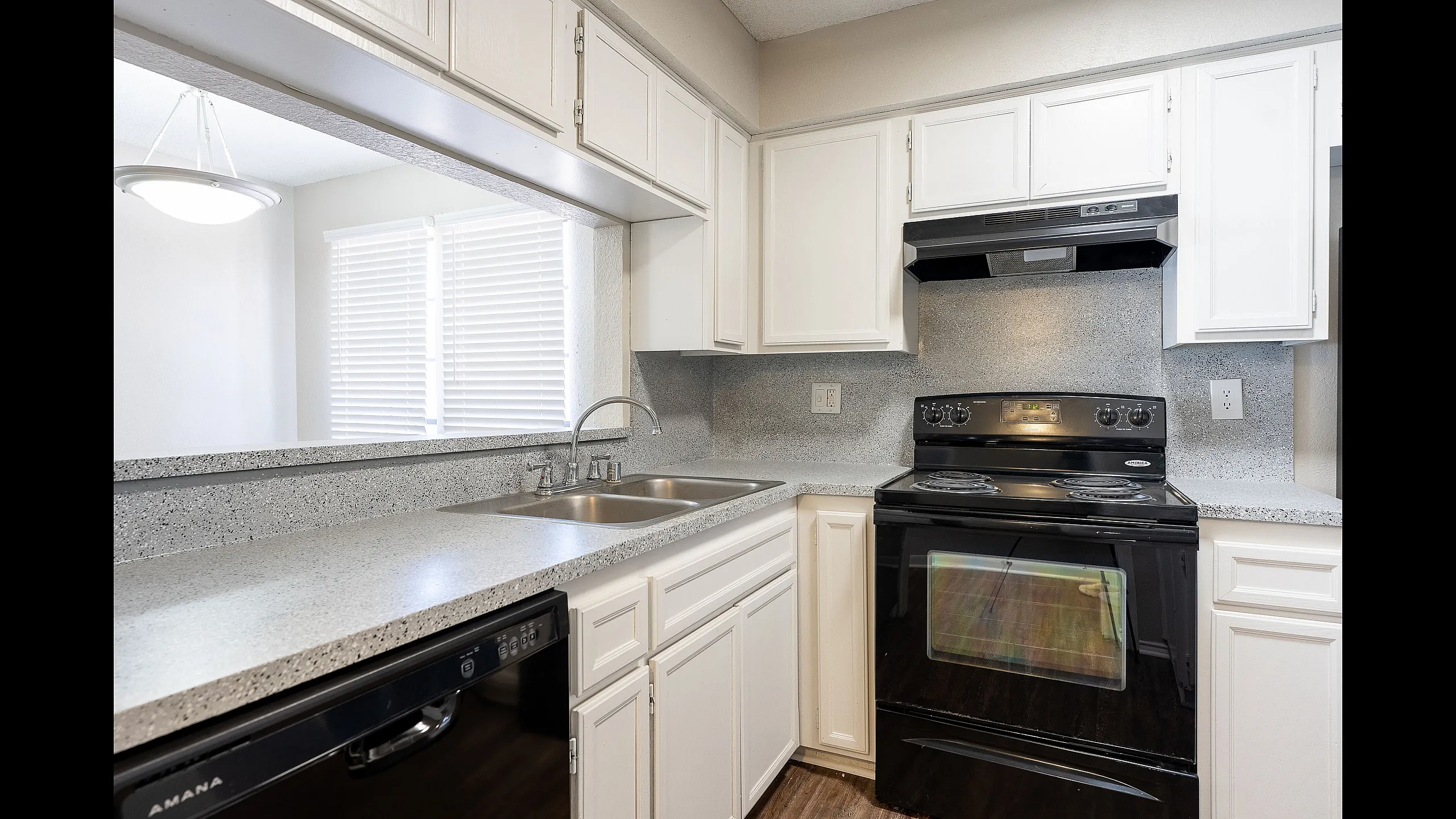 Bright and modern kitchen with sleek countertops, stylish black appliances, and abundant natural light.