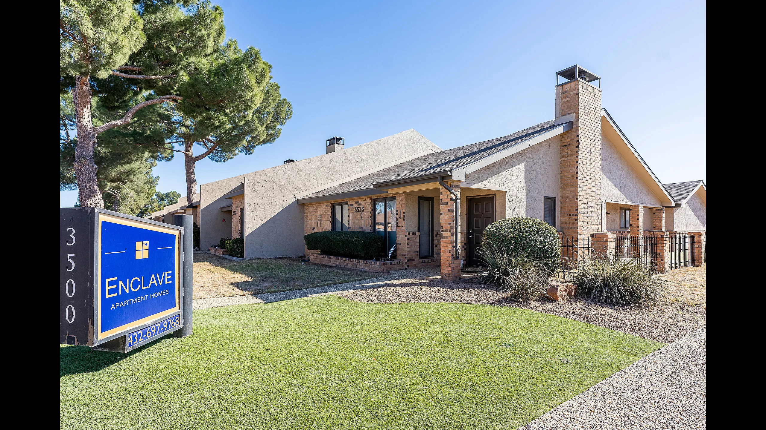 Charming Enclave Apartment Homes with rustic facade, manicured lawns, and inviting surroundings.