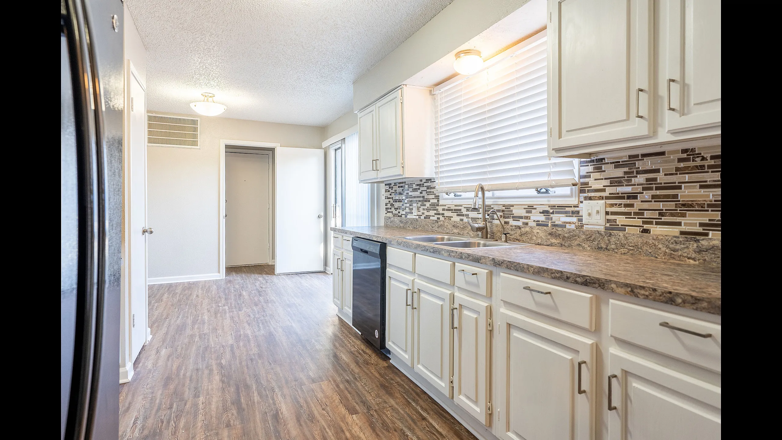 Bright and spacious kitchen with elegant wood flooring, modern cabinetry, and stylish backsplash, perfect for culinary creativity.