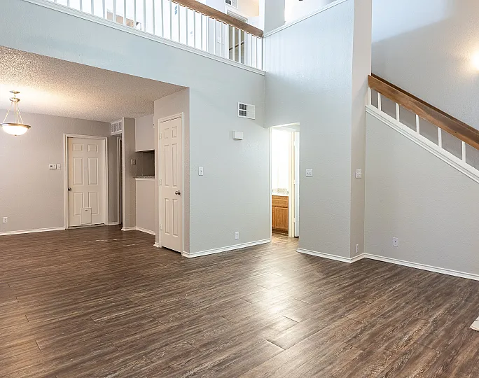 Bright open living space featuring elegant hardwood floors, modern lighting, and a stylish staircase leading to upper levels.