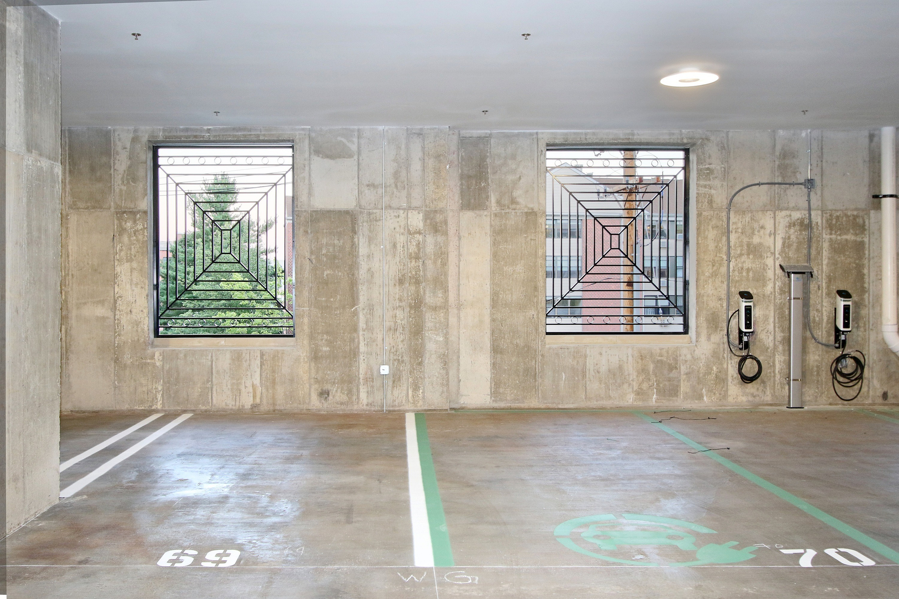 Spacious parking area with electric vehicle charging stations and large windows showcasing urban greenery.