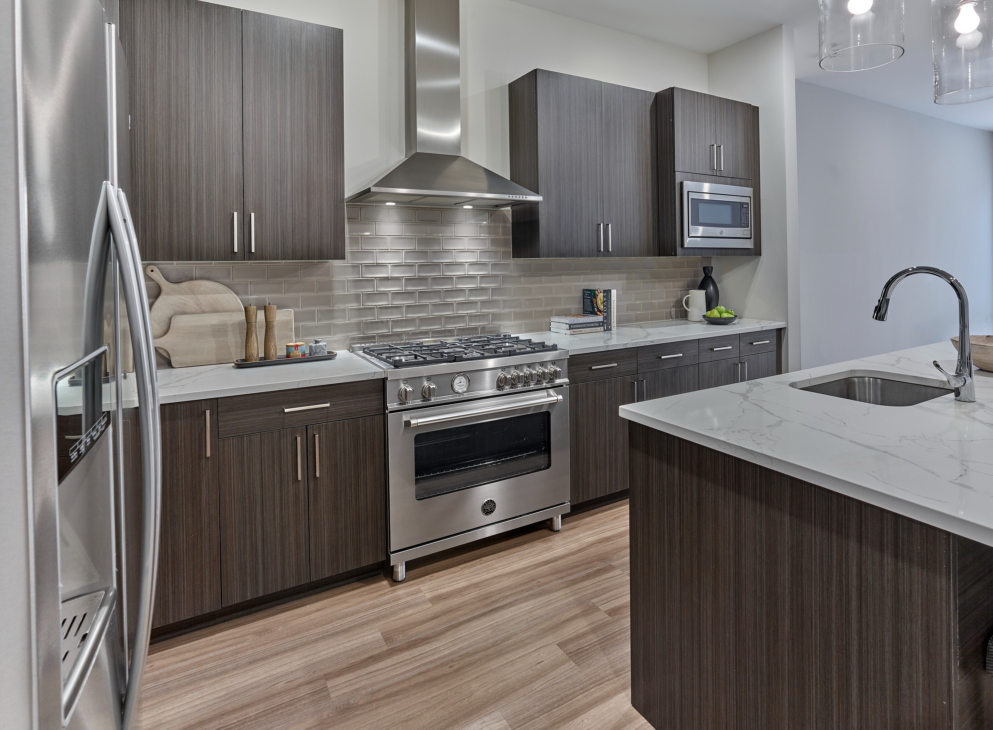 Contemporary kitchen with dark wood cabinets, silver appliances, and marble countertop.