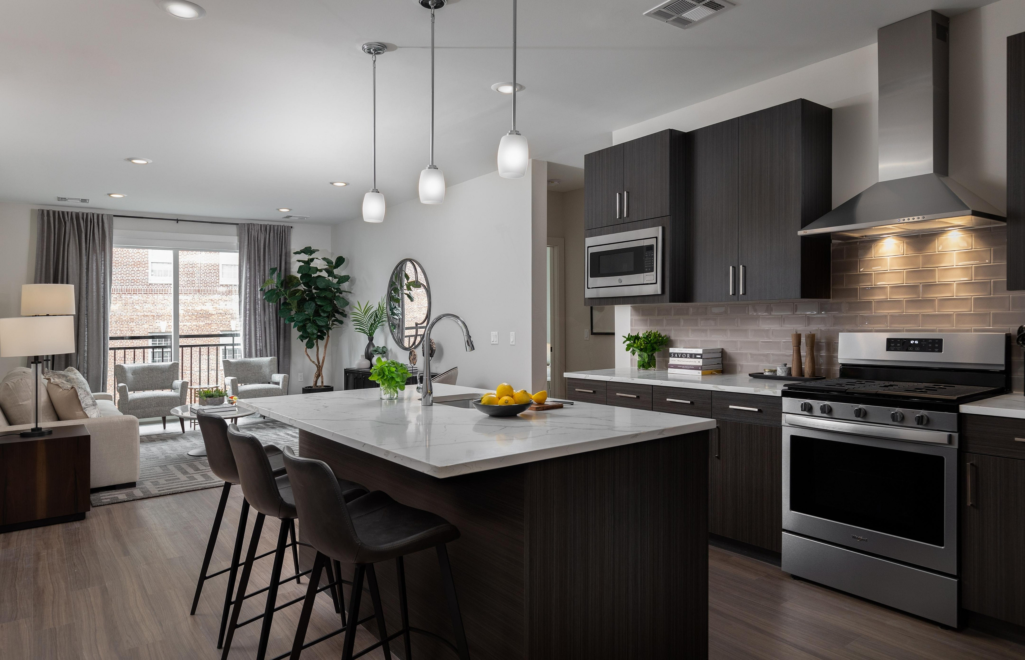 Modern open-concept kitchen and living room with sleek finishes, featuring a large island and stainless steel appliances.