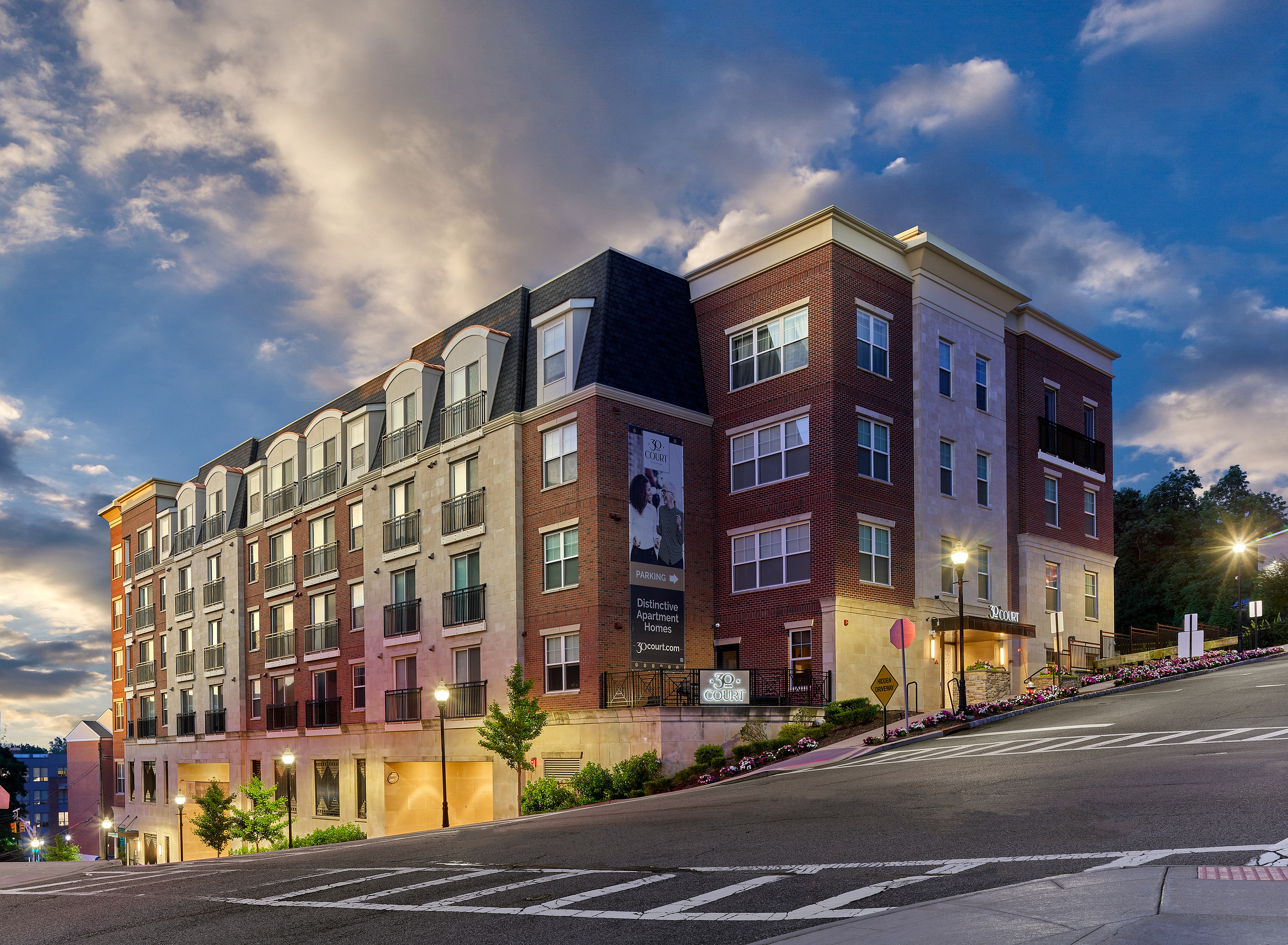 Modern apartment building with classic architecture against a vibrant evening sky.