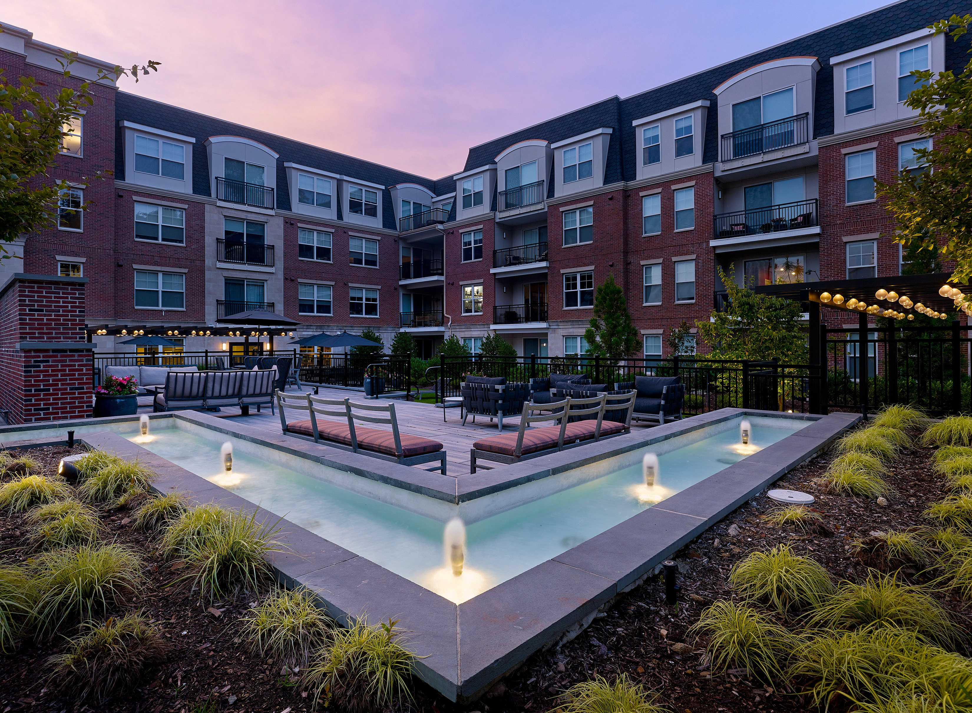 Sophisticated outdoor area of a modern apartment complex with a sleek water feature and stylish seating.