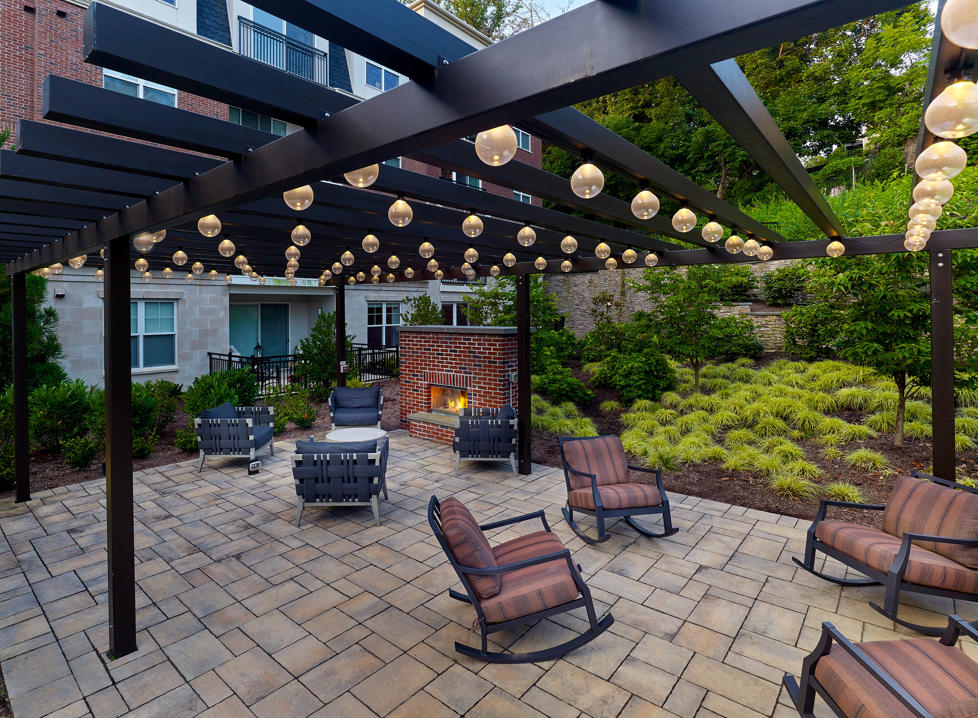Beautiful outdoor patio with pergola and cozy seating around a brick fireplace.
