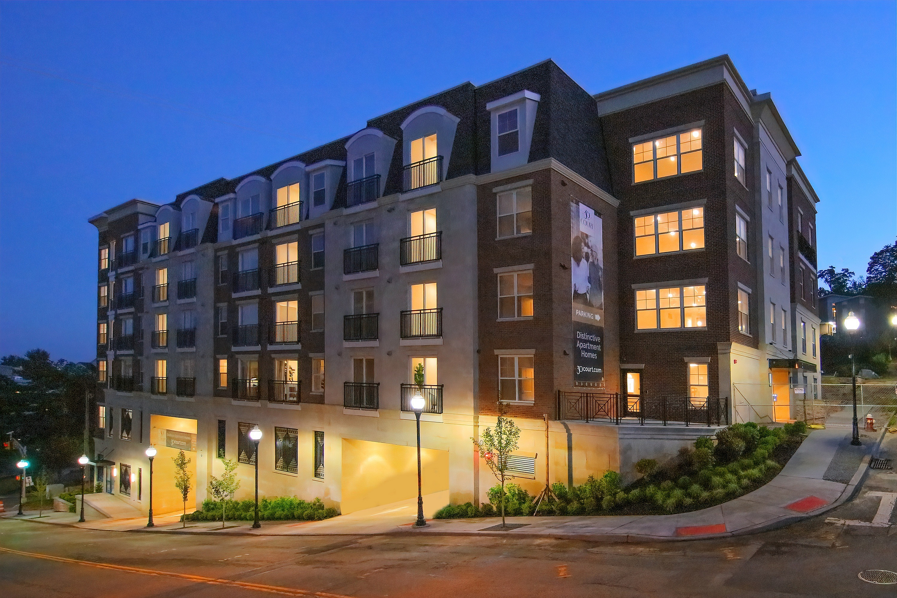 Charming apartment building with warm lighting, featuring elegant architectural design against a twilight sky.