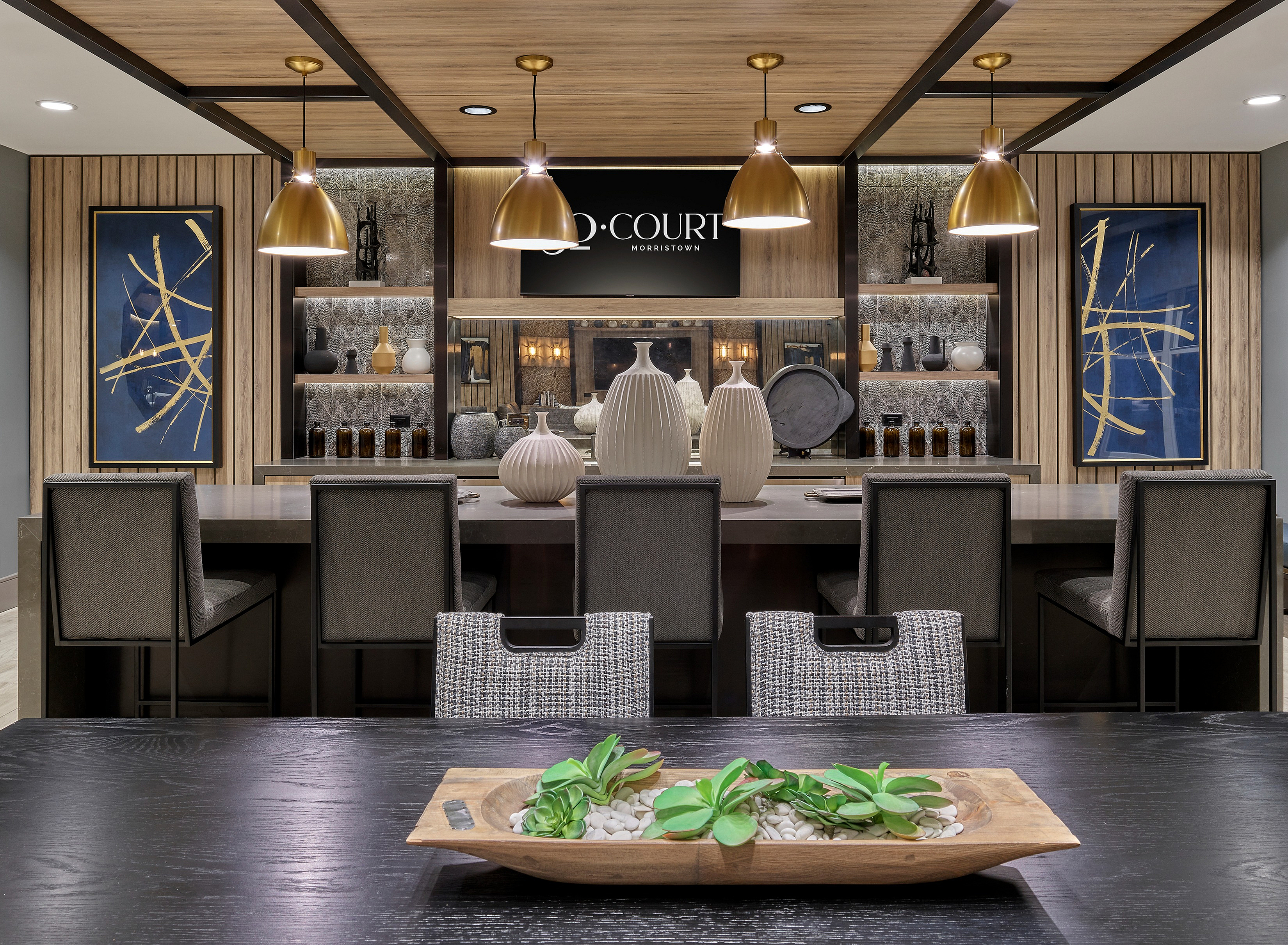 Chic dining area with plush chairs, stylish table settings, and modern decor under warm lighting.